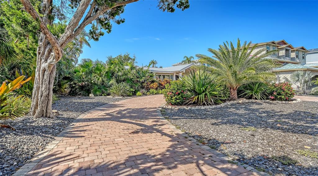 A brick paver path leads toward a house surrounded by tropical landscaping and palm trees — 602 BUTTONWOOD DRIVE, LONGBOAT KEY, FL