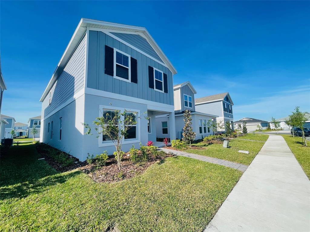 A two-story house with light blue siding and black shutters sits beside a concrete sidewalk — 6641 WILLOW VIEW AVENUE, ORLANDO, FL