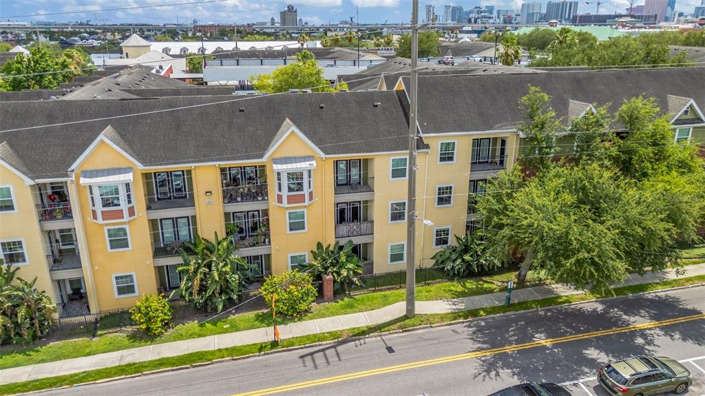 An exterior view of a multi-story yellow apartment building with balconies and a street — 1810 E PALM AVENUE UNIT 5217, TAMPA, FL