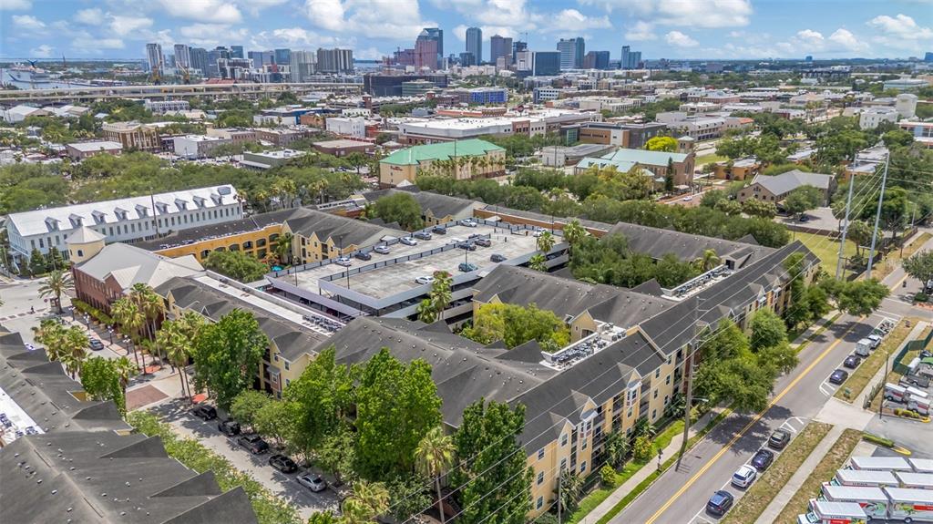 An aerial view shows a multi-story apartment complex with a central parking garage and city skyline — 1810 E PALM AVENUE UNIT 5217, TAMPA, FL