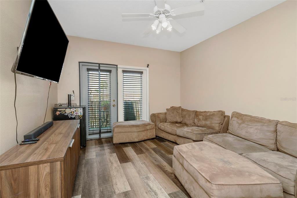 A living room features wood-look flooring, two tan sofas with ottomans, and a wall-mounted television — 1810 E PALM AVENUE UNIT 5217, TAMPA, FL