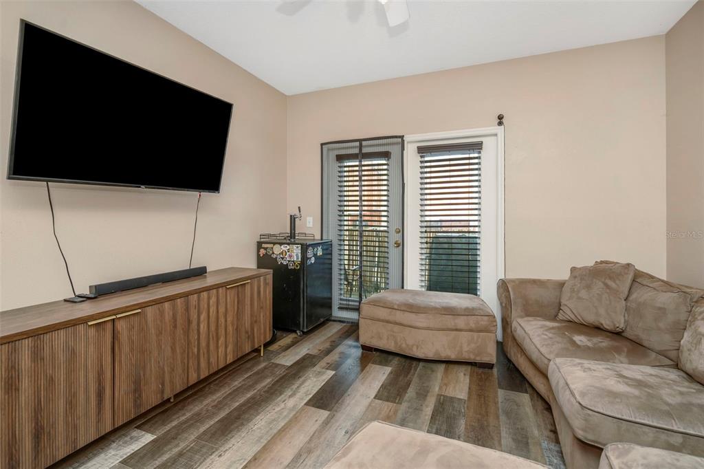 A living room features wood-look flooring, a wall-mounted television, a media console, and a sofa — 1810 E PALM AVENUE UNIT 5217, TAMPA, FL