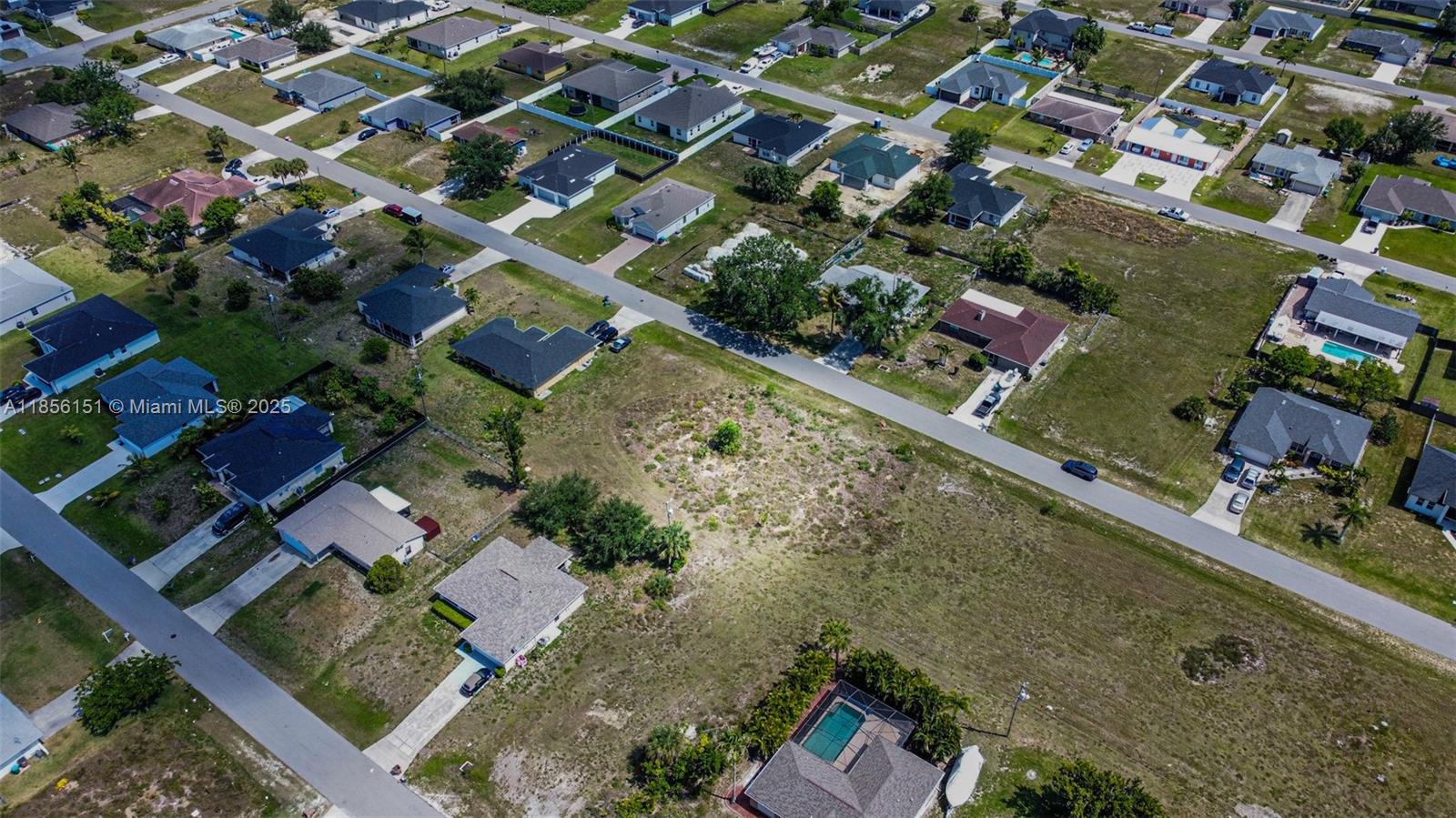 An aerial view shows a suburban neighborhood with single-family homes and a vacant lot — 309 NW 4th Ter, Cape Coral FL 33993, CAPE CORAL, FL
