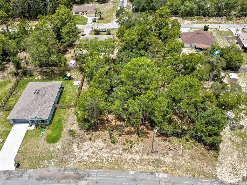 An aerial view shows a vacant, wooded residential lot situated between two existing houses — 9640 N SAN JOSE WAY, CITRUS SPRINGS, FL