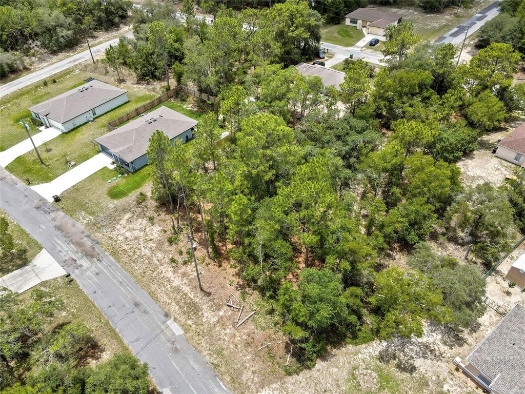 An aerial view shows a wooded residential lot situated between two houses and a road — 9640 N SAN JOSE WAY, CITRUS SPRINGS, FL