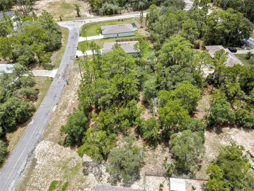 An aerial view shows a wooded residential lot situated between existing houses and a road — 9640 N SAN JOSE WAY, CITRUS SPRINGS, FL