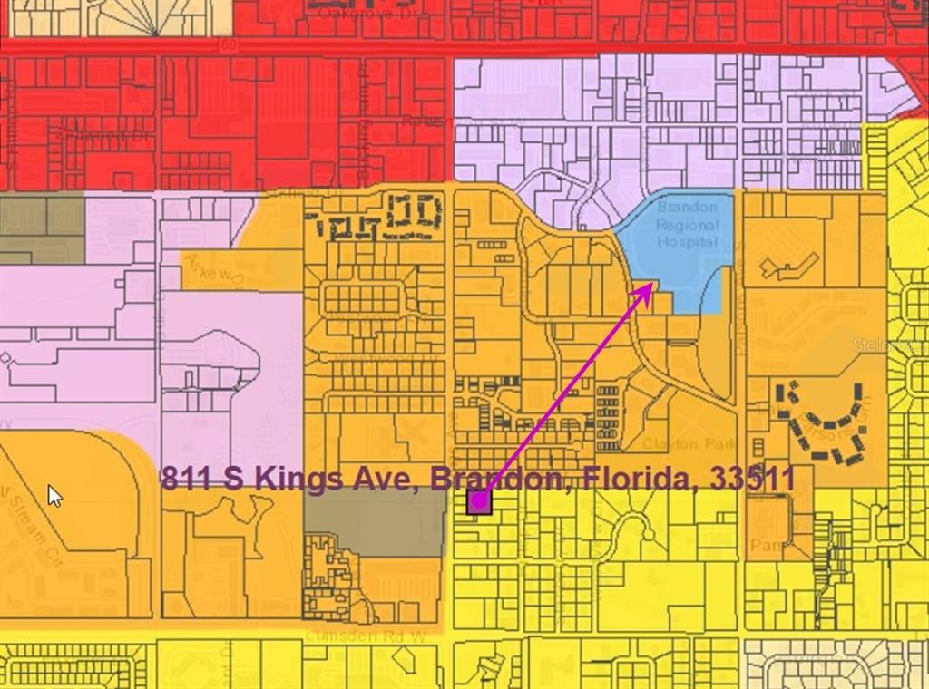 A vacant, fenced-in lot sits beside a paved road with a house in the background — 807 S KINGS AVENUE, BRANDON, FL