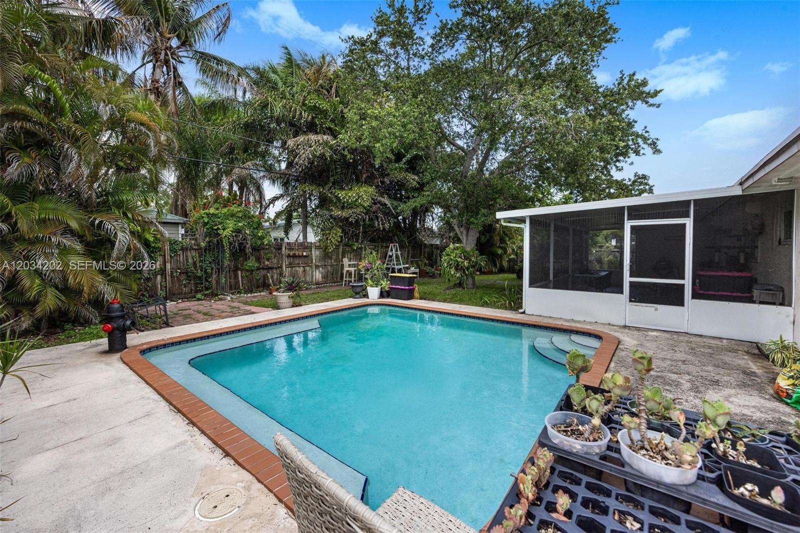 A backyard features a rectangular swimming pool, a screened-in patio, and lush landscaping — 8771 SW 200th Ter, Cutler Bay FL 33189, CUTLER BAY, FL