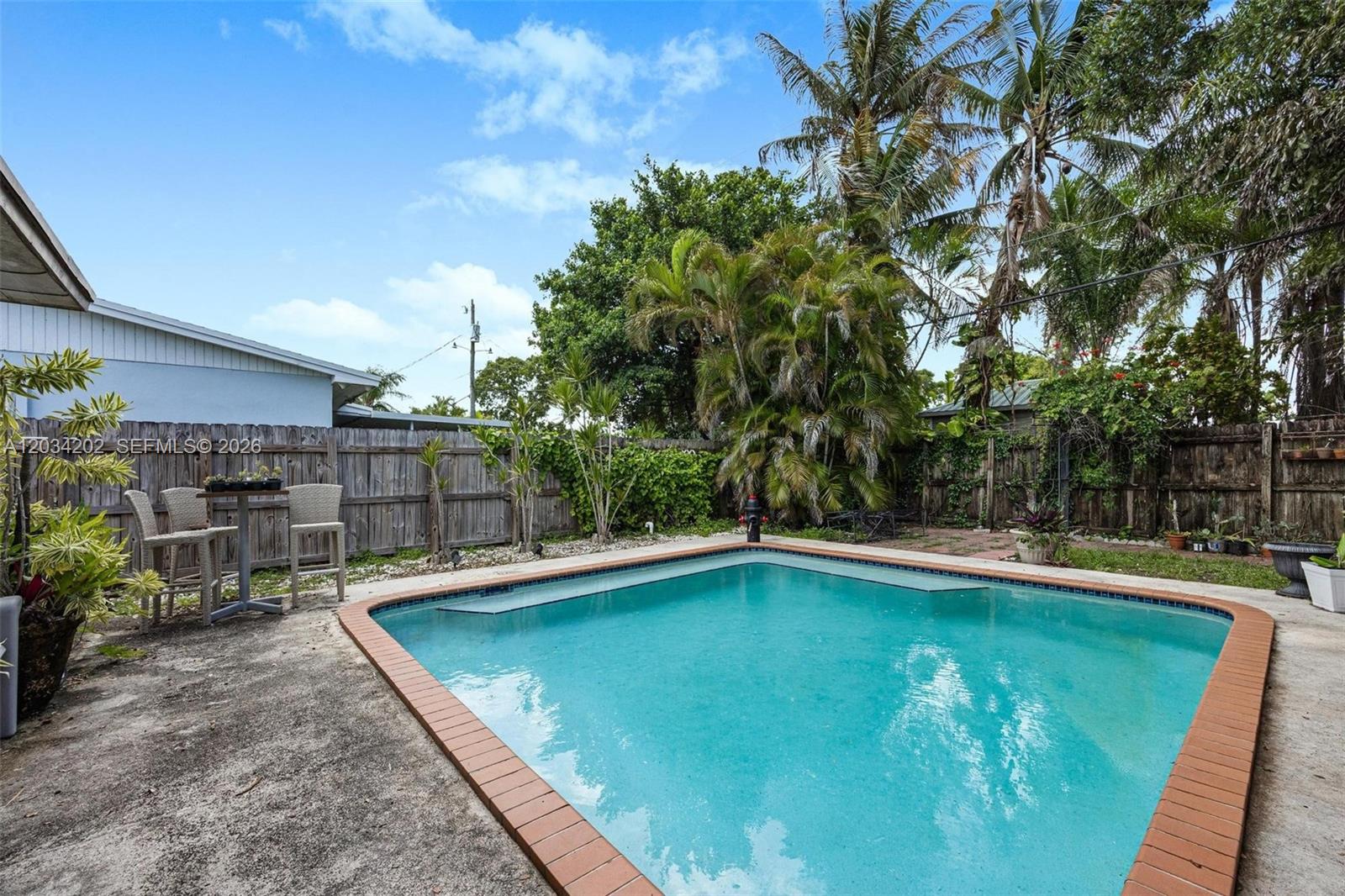 A backyard features a rectangular swimming pool with a brick border and a wooden fence — 8771 SW 200th Ter, Cutler Bay FL 33189, CUTLER BAY, FL
