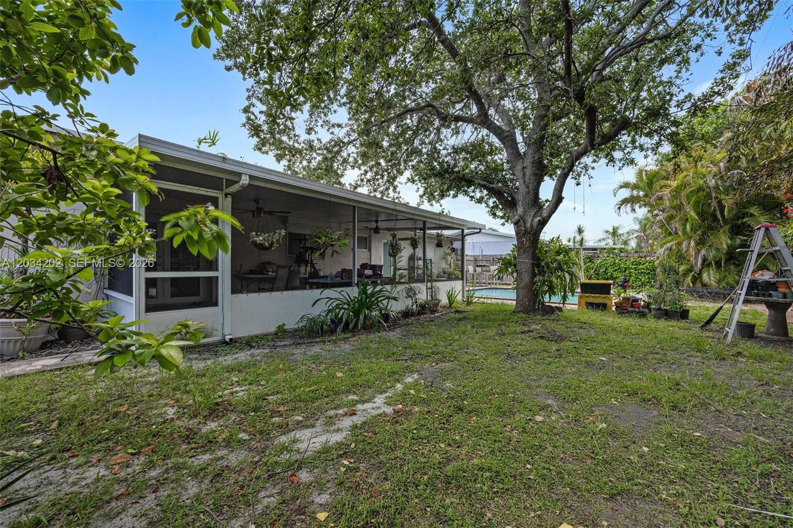 A screened-in patio overlooks a backyard with a large tree and a swimming pool — 8771 SW 200th Ter, Cutler Bay FL 33189, CUTLER BAY, FL