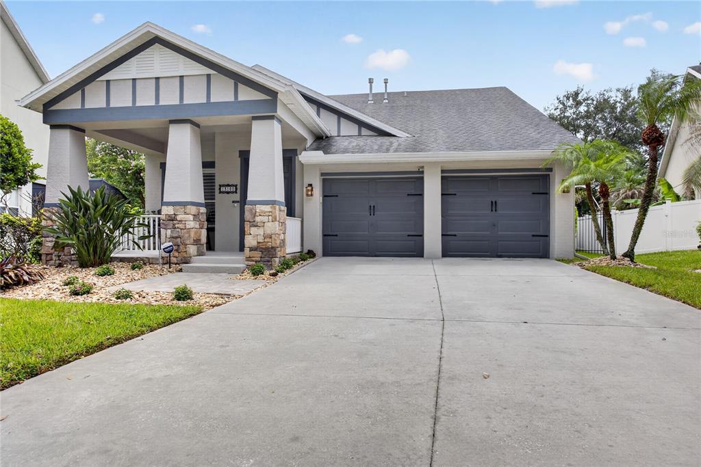 A single-story house features a stone-accented front porch, a two-car garage, and a concrete driveway — 13160 SUNKISS LOOP, WINDERMERE, FL