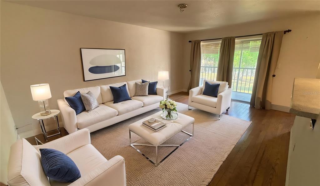A living room features white sofas, a central ottoman, and a sliding glass door — 7524 NEEDLE LEAF PLACE UNIT 32, TAMPA, FL