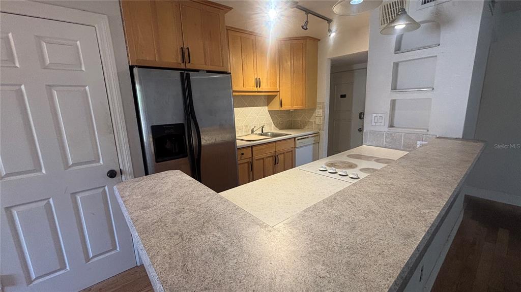 A kitchen features light wood cabinets, stainless steel appliances, and a light-colored laminate countertop — 7524 NEEDLE LEAF PLACE UNIT 32, TAMPA, FL
