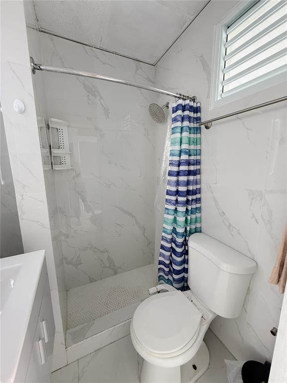 A bathroom features a walk-in shower with white marble-look tile and a white toilet — . BLASCOCHEA UNIT 311, CAROLINA, PR