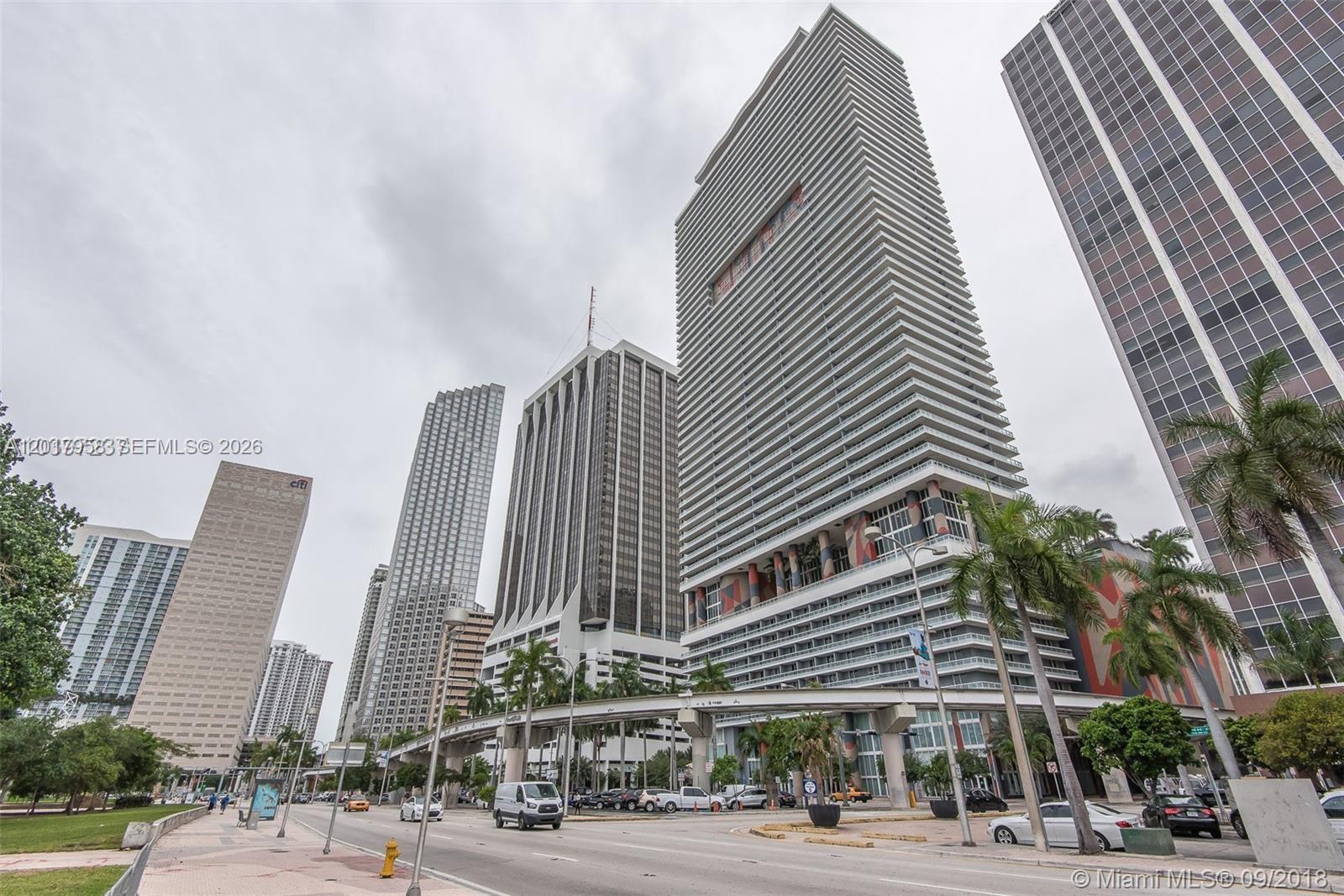 A street-level view of several high-rise buildings and an elevated train track in Miami — 50 Biscayne Blvd # 1801, Miami FL 33132, MIAMI, FL