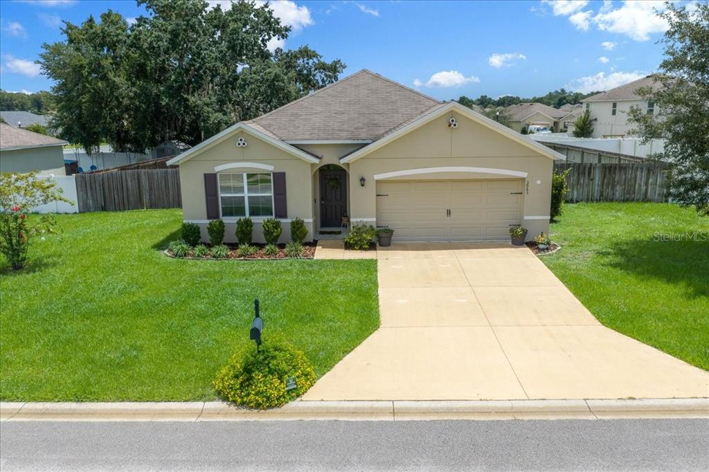 A single-story suburban house with a tan exterior, a two-car garage, and a front lawn — 3063 NE 42ND ROAD, OCALA, FL