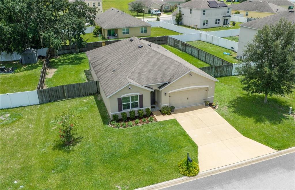 An aerial view of a single-story suburban house with a tan exterior and concrete driveway — 3063 NE 42ND ROAD, OCALA, FL