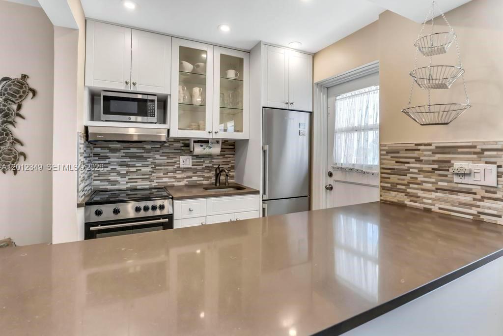 A kitchen features white cabinets, stainless steel appliances, a brown countertop, and a tiled backsplash — 901 S Surf Rd # 404, Hollywood FL 33019, HOLLYWOOD, FL