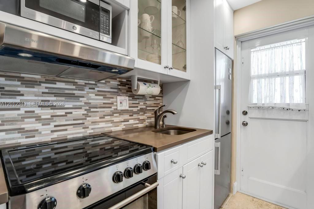A kitchen features a stainless steel stove, a small sink, and white cabinetry — 901 S Surf Rd # 404, Hollywood FL 33019, HOLLYWOOD, FL
