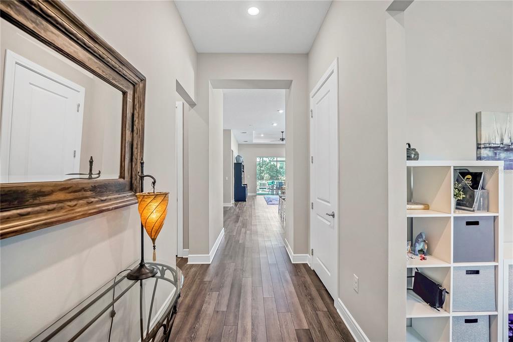 A hallway with wood-look flooring leads from a foyer toward an open living area — 9336 SW 56TH LOOP, OCALA, FL