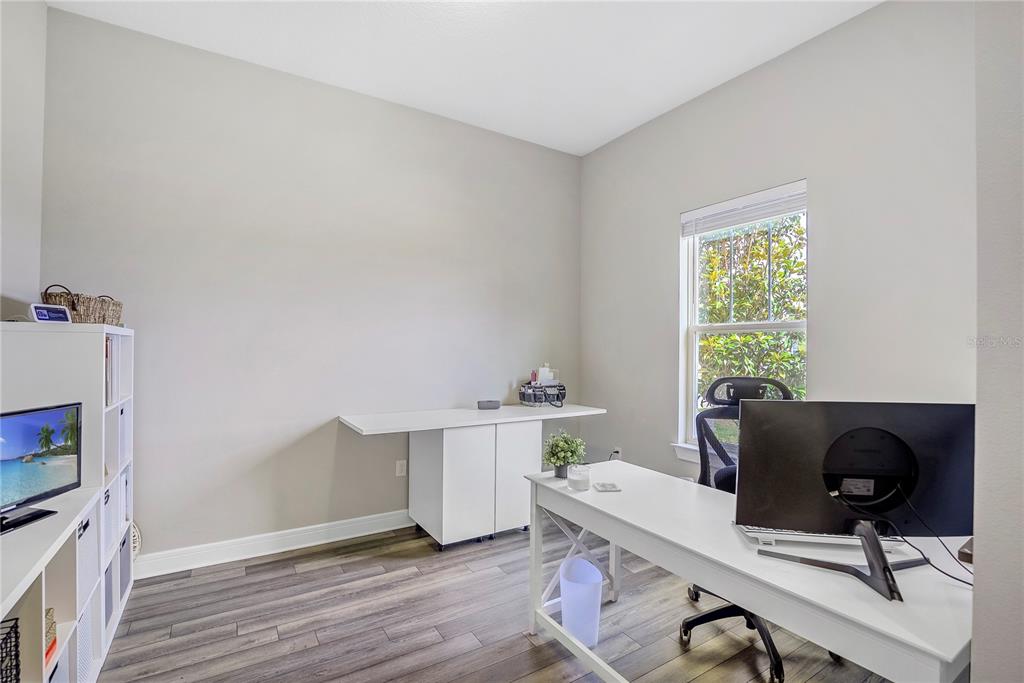 A home office features a white desk, a storage unit, a bookshelf, and wood-look flooring — 9336 SW 56TH LOOP, OCALA, FL