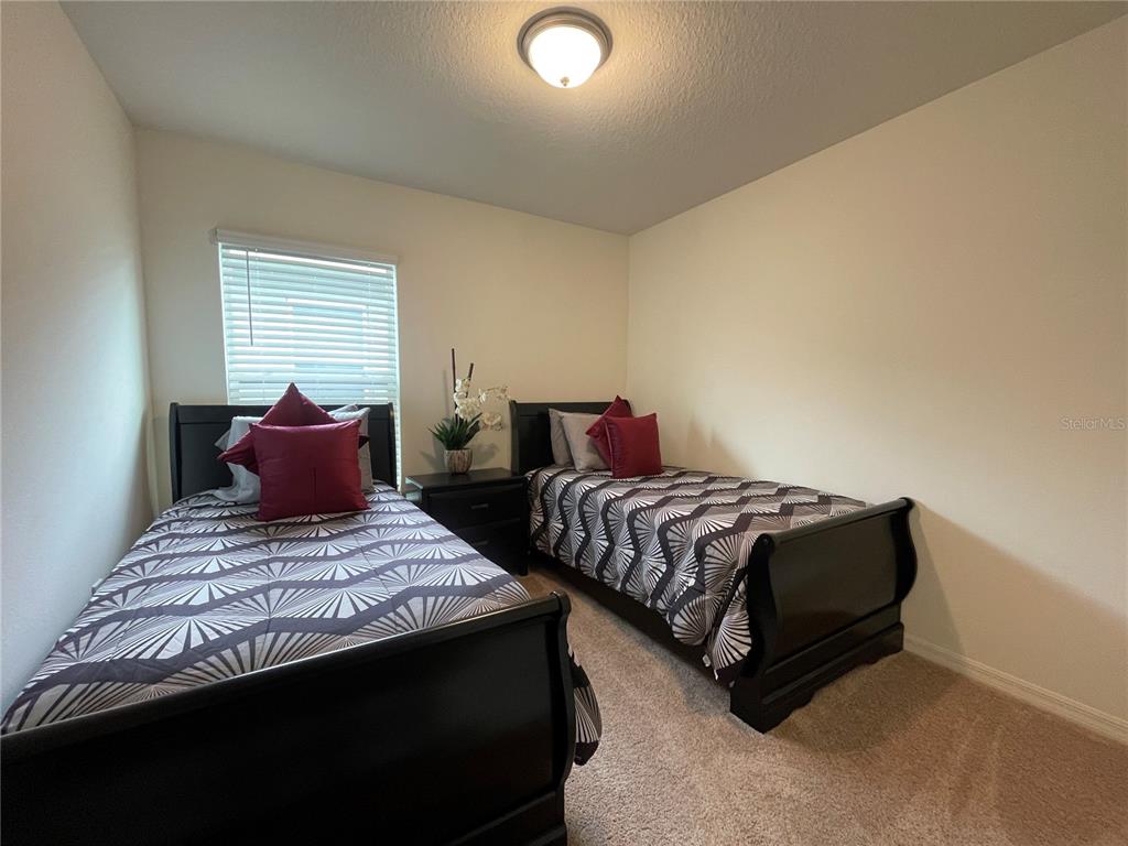 A bedroom features two twin beds with dark wood frames and patterned bedding — 7115 CRUZ COURT, LAKELAND, FL