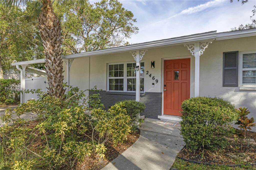 A single-story house exterior features a red front door, gray brick accents, and landscaping — 2469 WALDEMERE STREET, SARASOTA, FL