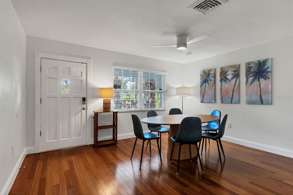 A dining room features a round wooden table, dark chairs, and palm tree wall art — 2469 WALDEMERE STREET, SARASOTA, FL