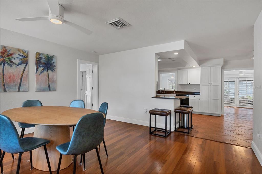 A dining area with a round wooden table and blue chairs opens to a kitchen — 2469 WALDEMERE STREET, SARASOTA, FL