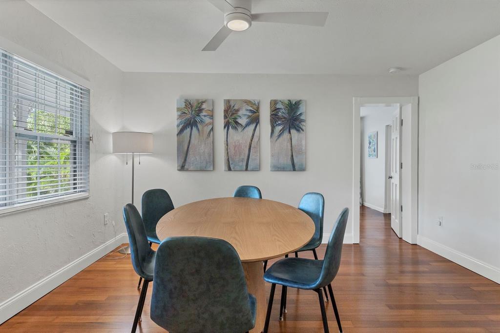A dining room features a round wooden table, six blue chairs, and palm tree artwork — 2469 WALDEMERE STREET, SARASOTA, FL