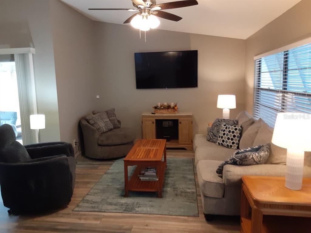 A living room features a television, a sofa, an armchair, and a wooden coffee table — 6625 GASPARILLA PINES BOULEVARD, ENGLEWOOD, FL