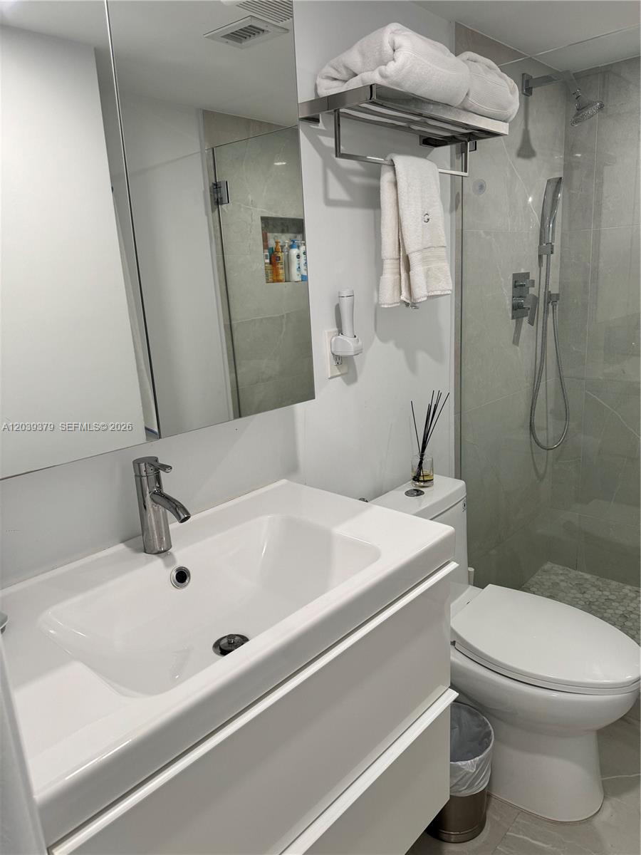 A modern bathroom features a white vanity, a glass-enclosed shower, and a wall-mounted towel rack — 1865 Brickell Ave # A1411, Miami FL 33129, MIAMI, FL