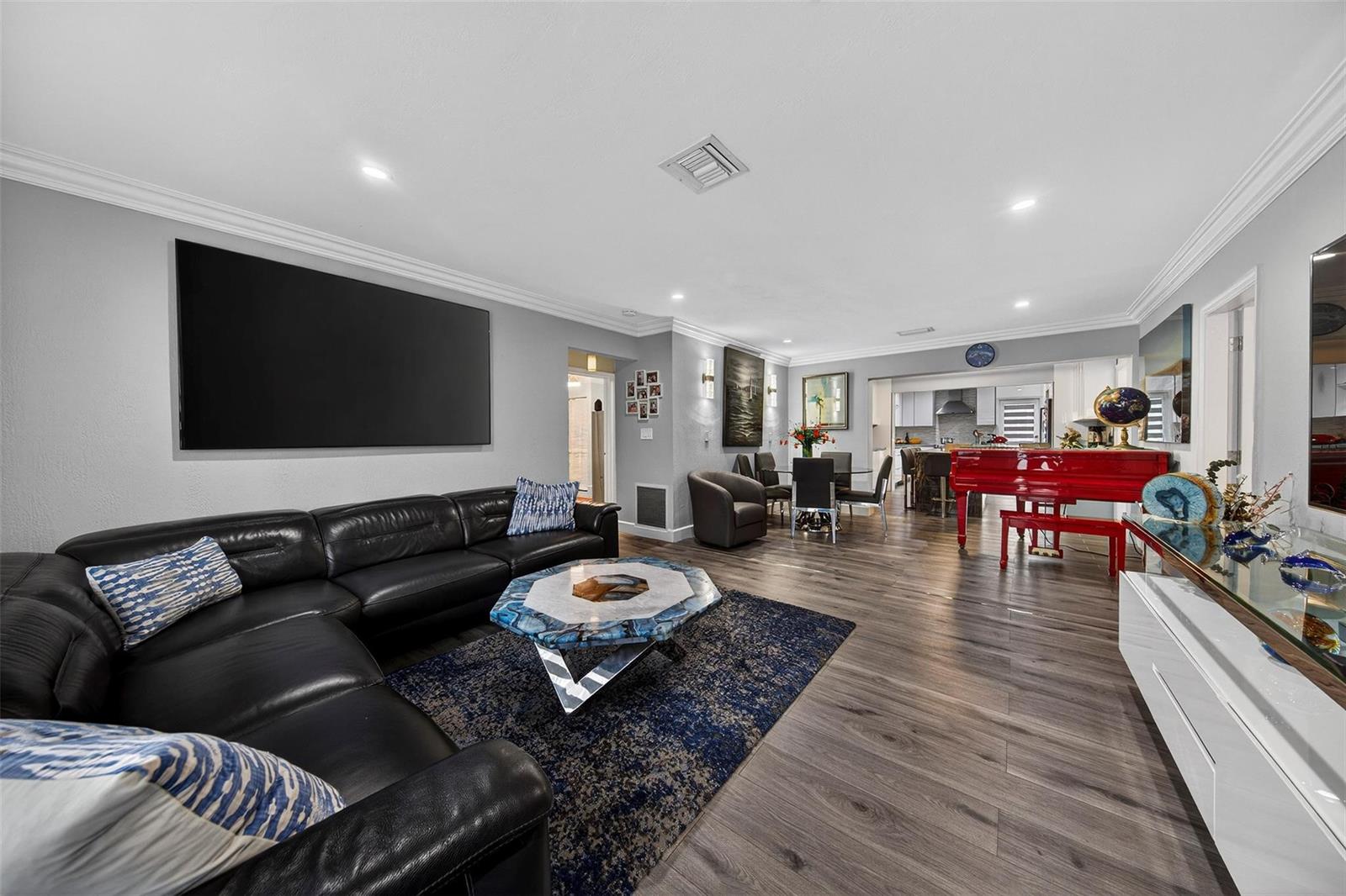 A living room features a black leather sectional, a blue agate coffee table, and a red piano — 918 NE 4th Street, Hallandale Beach FL 33009, HALLANDALE BEACH, FL