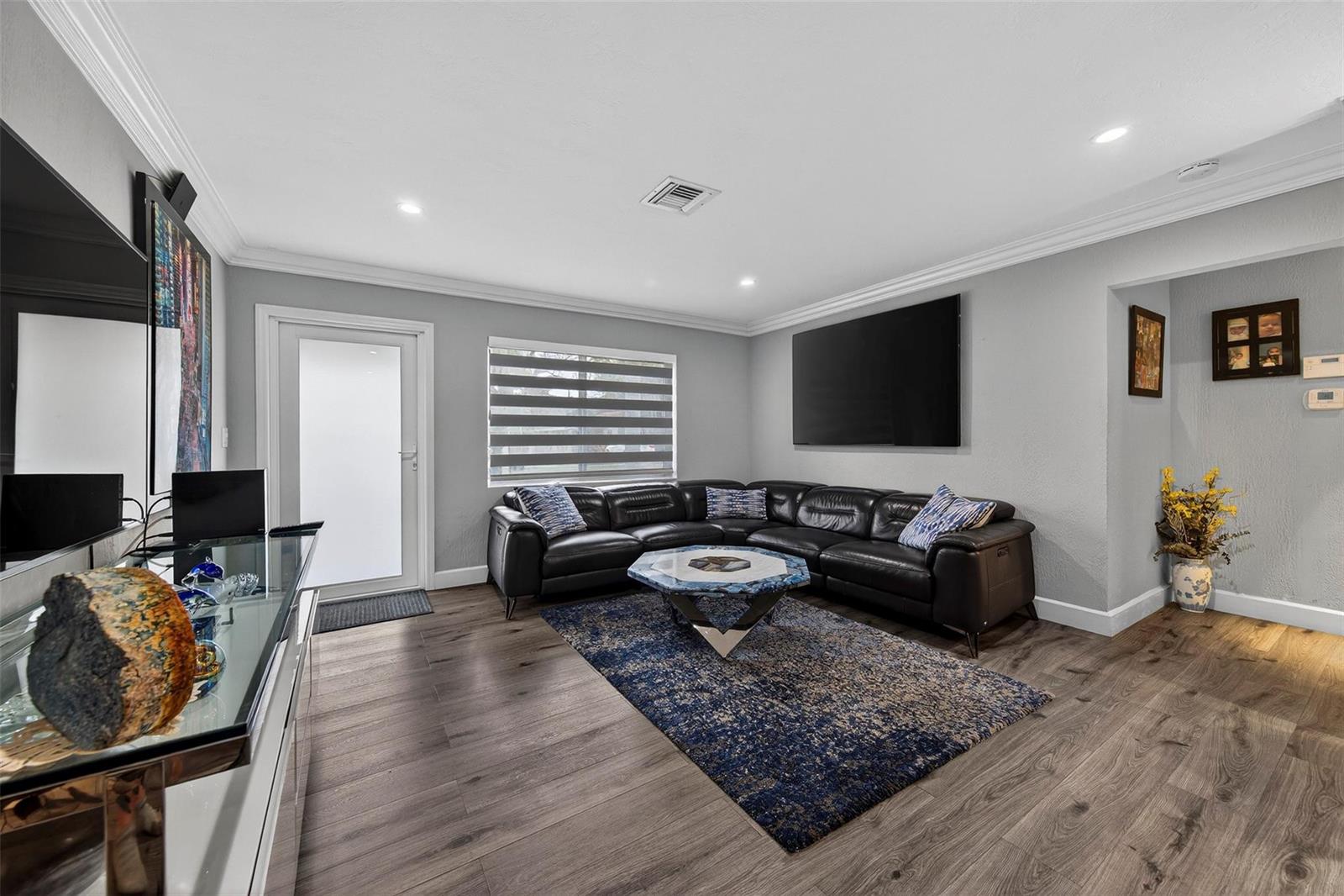 A living room features a black leather sectional, a blue patterned rug, and wood flooring — 918 NE 4th Street, Hallandale Beach FL 33009, HALLANDALE BEACH, FL