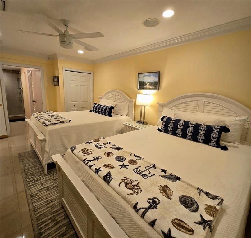 A bedroom features two white beds with nautical-themed runners and a ceiling fan — 36750 US HIGHWAY 19 N UNIT 11-104, PALM HARBOR, FL