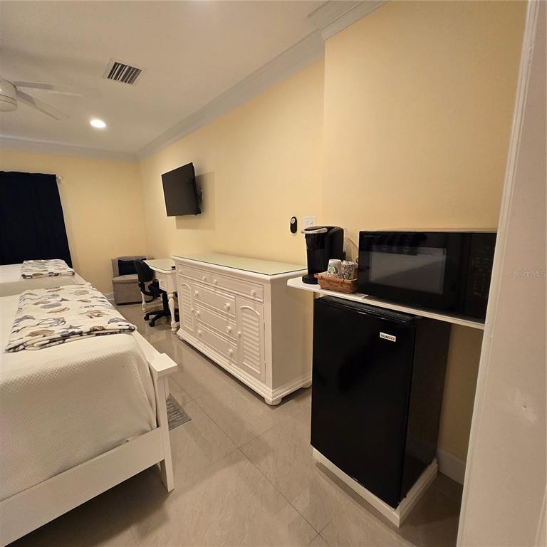 A bedroom features two beds, a white dresser, a desk, and a microwave on a refrigerator — 36750 US HIGHWAY 19 N UNIT 11-104, PALM HARBOR, FL
