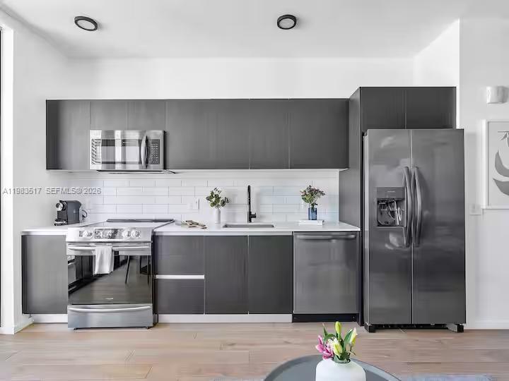 A modern kitchen features dark gray cabinetry, stainless steel appliances, and a white subway tile backsplash — 398 NE 5th St # 3516, Miami FL 33132, MIAMI, FL