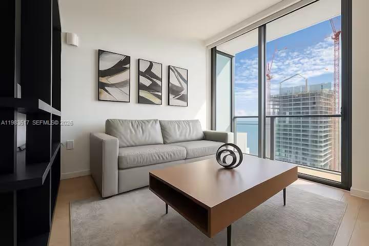 A modern living room features a grey sofa, coffee table, and floor-to-ceiling windows with views — 398 NE 5th St # 3516, Miami FL 33132, MIAMI, FL