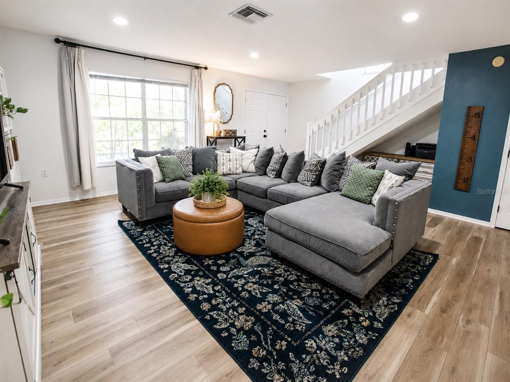 A living room features a large gray sectional sofa, a round ottoman, and a patterned rug — 2384 HOUNDS TRAIL, PALM HARBOR, FL
