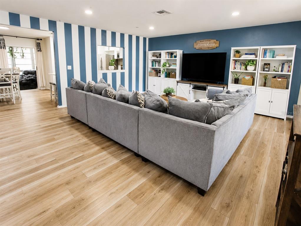 A living room features a large gray sectional sofa, striped walls, and white bookshelves — 2384 HOUNDS TRAIL, PALM HARBOR, FL