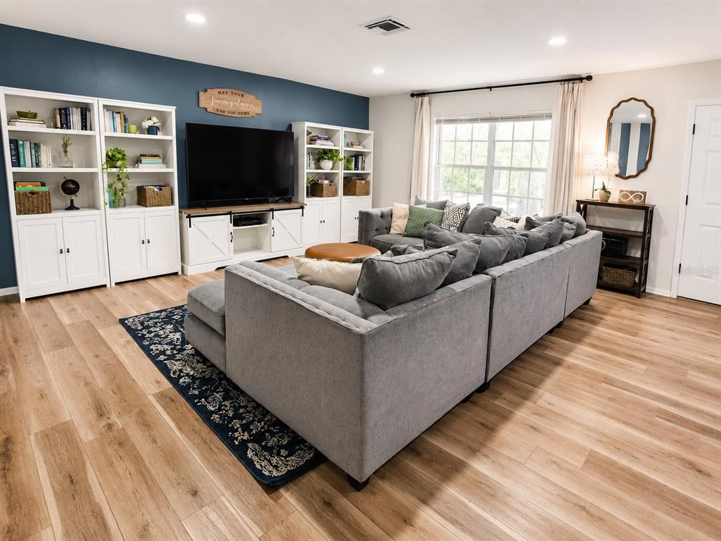 A living room features a large gray sectional sofa, built-in white shelving, and a television — 2384 HOUNDS TRAIL, PALM HARBOR, FL
