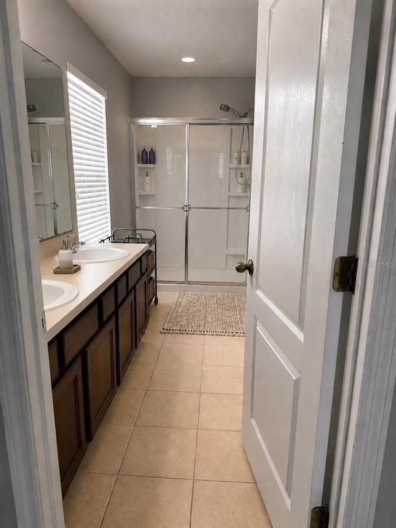 A bathroom features a double vanity with dark cabinets, a walk-in shower, and tile flooring — 3913 PEMBERLY, ST CLOUD, FL