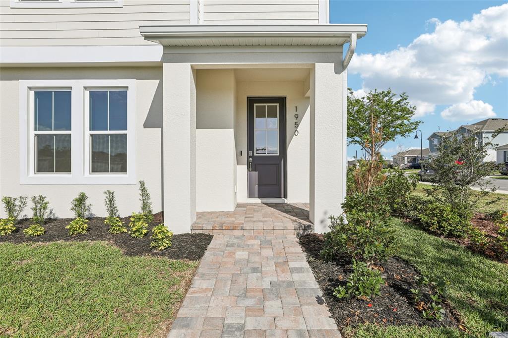A paved walkway leads to the front entrance of a house with light-colored siding — 1950 EDUCATION STREET, ST CLOUD, FL