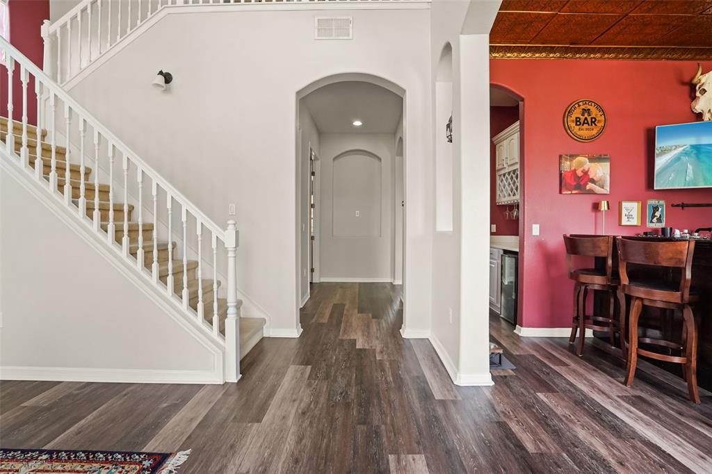 A staircase with white railings sits beside a hallway and a red-walled bar area — 1699 SWALLOWTAIL LANE, SANFORD, FL