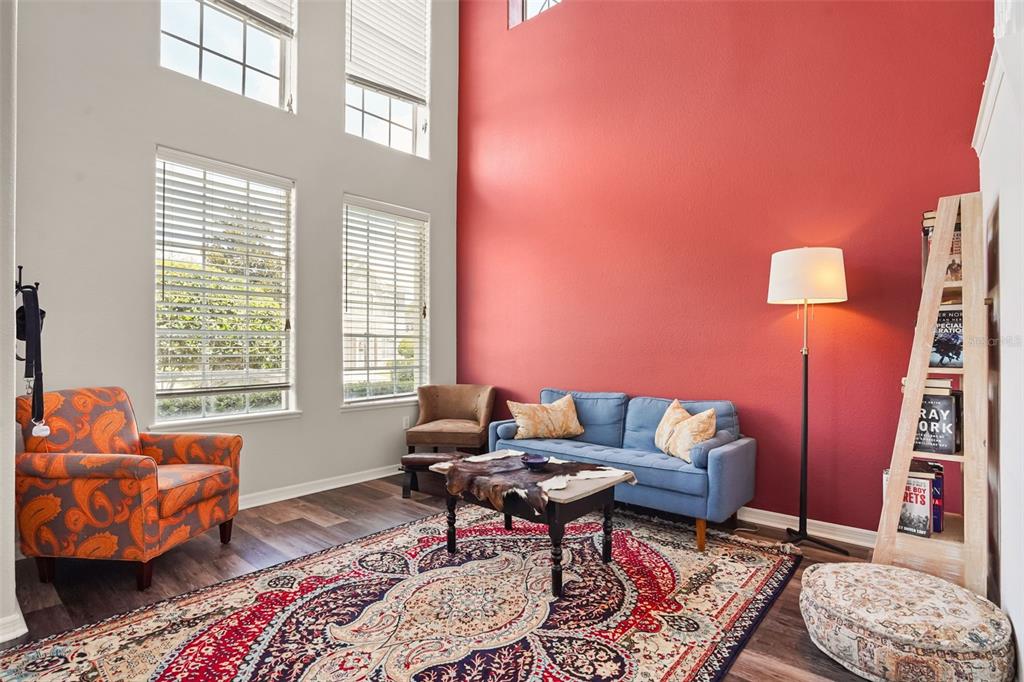 A living room features a red accent wall, a blue sofa, and a patterned rug — 1699 SWALLOWTAIL LANE, SANFORD, FL