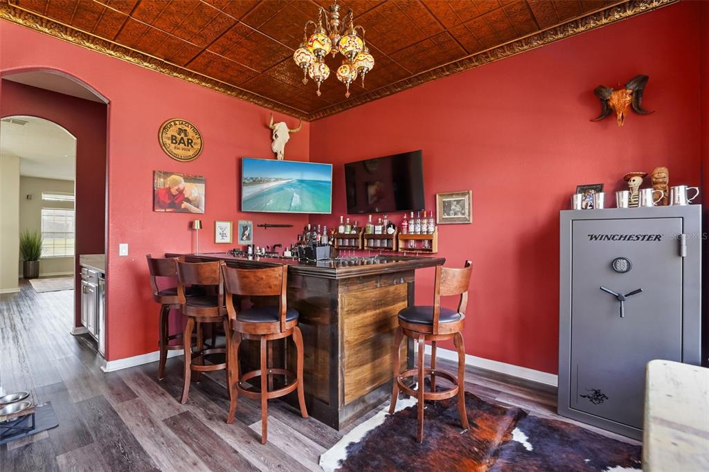 A home bar features a wooden counter, red walls, a decorative ceiling, and a gun safe — 1699 SWALLOWTAIL LANE, SANFORD, FL