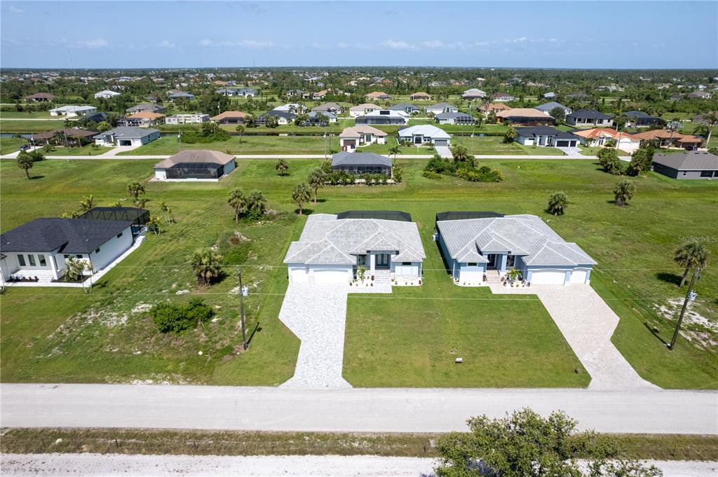 An aerial view shows a house with a tiled roof, a pool enclosure, and a driveway — 221 ROTONDA BOULEVARD S, ROTONDA WEST, FL