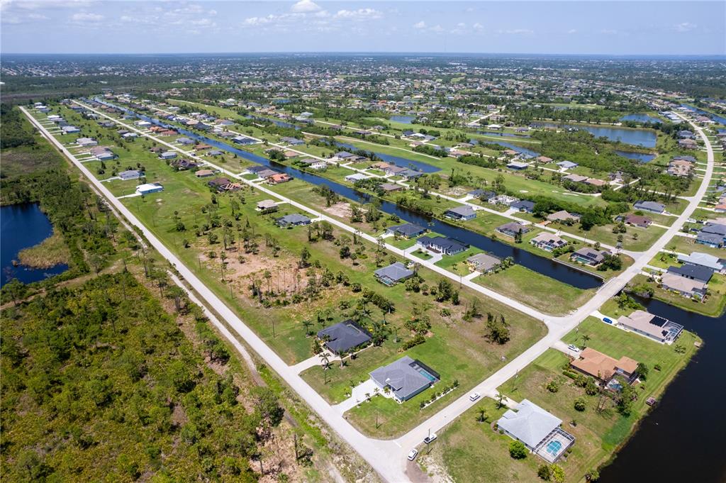 An aerial view shows two modern suburban houses with paved driveways and surrounding grassy lots — 221 ROTONDA BOULEVARD S, ROTONDA WEST, FL