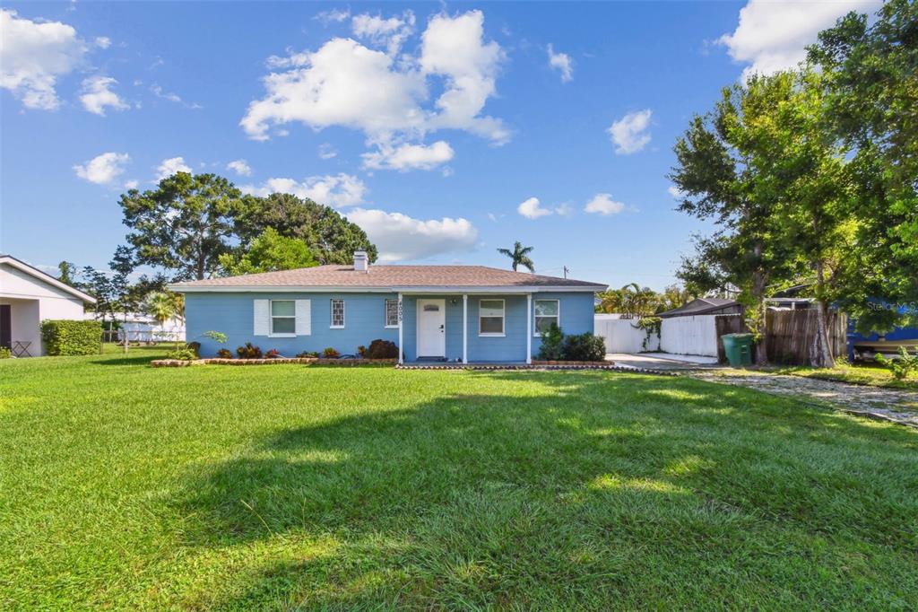 A single-story blue house with a white front door sits on a large grassy lot — 4005 W TYSON AVENUE, TAMPA, FL