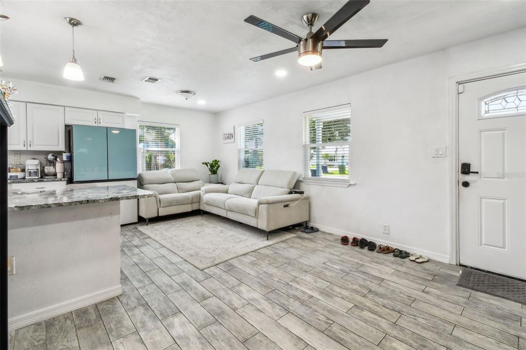 A living room with light-colored sofas, a ceiling fan, and tile flooring near an entryway — 4005 W TYSON AVENUE, TAMPA, FL